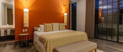 A modern bedroom with a large bed, a bench, a small table, and a large window with curtains.