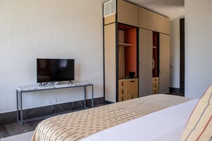 Ein modernes Hotelzimmer mit einem Bett, einem Fernseher auf einer Marmorkonsole und einem Kleiderschrank mit Schiebetüren.