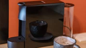 A coffee machine with two cups of coffee on a wooden tray against an orange wall.