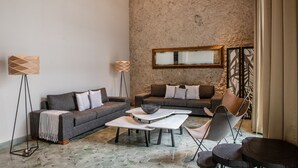 A modern living room with two sofas, a coffee table, and a chair. There is a floor lamp and a mirror on the wall. - Antelar Casa Destino (Mérida)