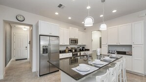 A modern kitchen with white cabinetry, stainless steel appliances, a granite countertop, and pendant lighting. - Amazing New 5 Bedroom 4.5 Bathroom Townhome with Private Pool (Davenport)