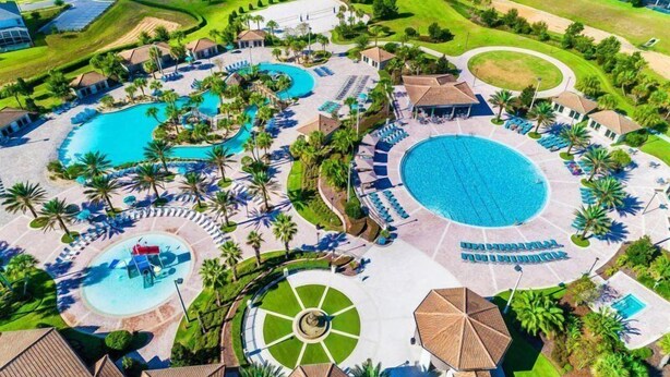Een resort met meerdere zwembaden, ligbedden en palmbomen.