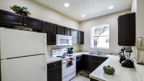 A modern kitchen with dark cabinets, white appliances, a large window, and a blender on the counter. - Amazing Townhouse 4Bdr 3Bth Spa Resort near Disney (Davenport)