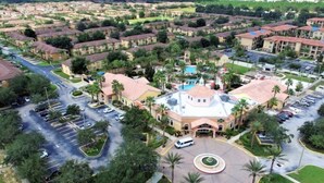 An aerial view of a residential area with multiple apartment buildings, a central plaza with a fountain, and a parking lot. - Amazing Townhouse 4Bdr 3Bth Spa Resort near Disney (Davenport)