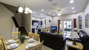 A modern living room with a dining area, a kitchen, and a staircase. - Amazing Townhouse 4Bdr 3Bth Spa Resort near Disney (Davenport)