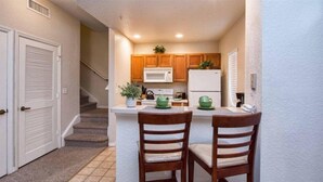 A compact kitchen with wooden cabinets, a white refrigerator, a microwave, and a small island with two chairs. - Great location 4Bed 3bth Townhouse with kids themed room (Kissimmee)