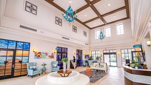 A spacious lobby with a large white sofa, a wooden deck with a sunset view, and a reception desk. - Amazing New TownHome 5 Bdr 4,5 Bath with Pvt Pool and Access to Clubhouse,15min from Disney (Kissimmee)