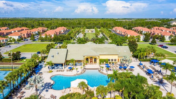A resort with a central pool, multiple buildings, and a well-maintained lawn.