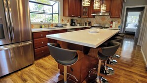 A modern kitchen with a large island, stainless steel appliances, wooden cabinets, and pendant lighting. - A Luxury Urban Getaway Walk to Stanford #2333 (Palo Alto)