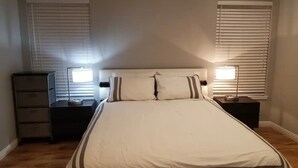 A bedroom with a bed, two bedside tables, a dresser, and two windows with blinds. - A Luxury Urban Getaway Walk to Stanford #2333 (Palo Alto)