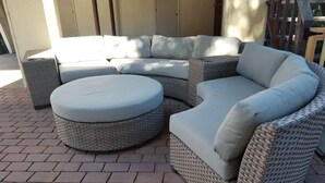 A wicker sectional sofa with a round ottoman, set on a brick patio. - A Luxury Urban Getaway Walk to Stanford #2333 (Palo Alto)