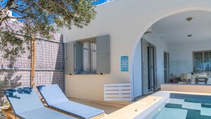 Ein Poolbereich mit zwei Liegestühlen, einem kleinen Pool und einer überdachten Terrasse.
