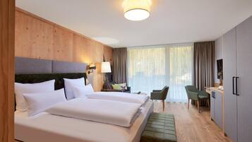 A hotel room with two beds, a desk, a chair, a TV, and a large window with curtains.