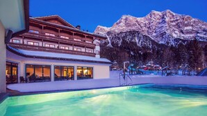 Ett hotell med en pool, en skidlift och snötäckta berg i bakgrunden.