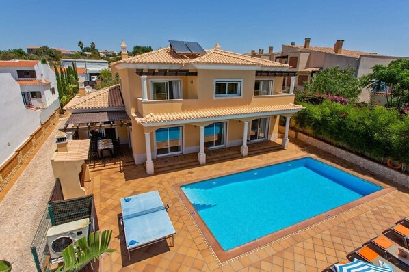 Ein zweistöckiges Haus mit Swimmingpool, Gartenmöbeln und einem Garten.
