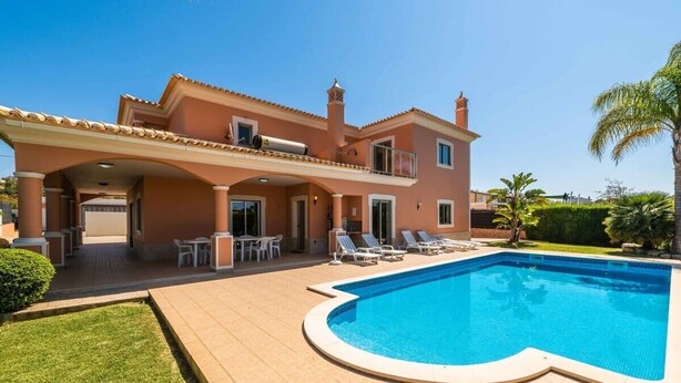 Una casa de dos pisos con piscina, mobiliario exterior y césped bien cuidado.