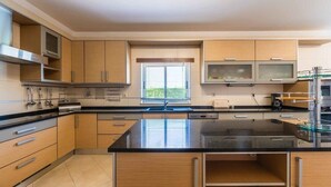 Una cocina moderna con armarios de madera, encimera negra y electrodomésticos de acero inoxidable.