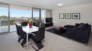 Una sala de estar moderna con comedor, ventanas grandes y vista a la ciudad.