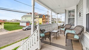 A covered porch with wicker furniture and a view of a street. - Romantic Queen Suite 1 Block to Beach & Asbury | Victorian Charm | 1000 Mbps ... (Neptune Township)