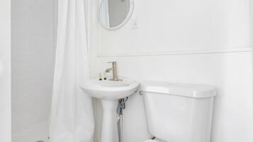 Een badkamer met een wit wastafel, toilet en douchegordijn.