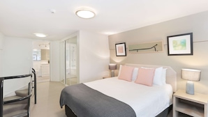 A modern bedroom with a bed, bedside tables, a mirror, and a staircase.