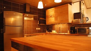 Een moderne keuken met houten kastjes, een roestvrijstalen koelkast, een magnetron en een koffiezetapparaat.