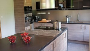 A modern kitchen with a central island, stainless steel appliances, and light wood cabinetry.