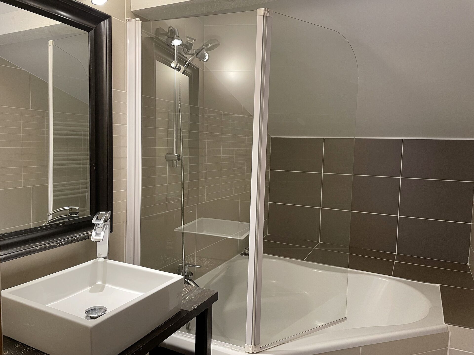 A bathroom with a white sink, a bathtub, and a glass-enclosed shower.