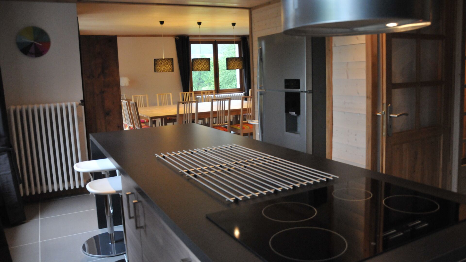 A modern kitchen with a central island, stainless steel appliances, and a dining area with chairs and a table.