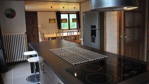 A modern kitchen with a central island, stainless steel appliances, and a dining area with chairs and a table.