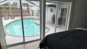 Ett sovrum med en stor skjutdörr i glas som leder ut till poolområdet.