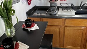 A kitchen with a black countertop, a coffee maker, and a red and white checkered cloth hanging above the sink. - Pool Guesthouse near Hollywood & Studios (Burbank)