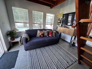 A living room with a sofa, patterned rug, and a television. - Pool Guesthouse near Hollywood & Studios (Burbank)