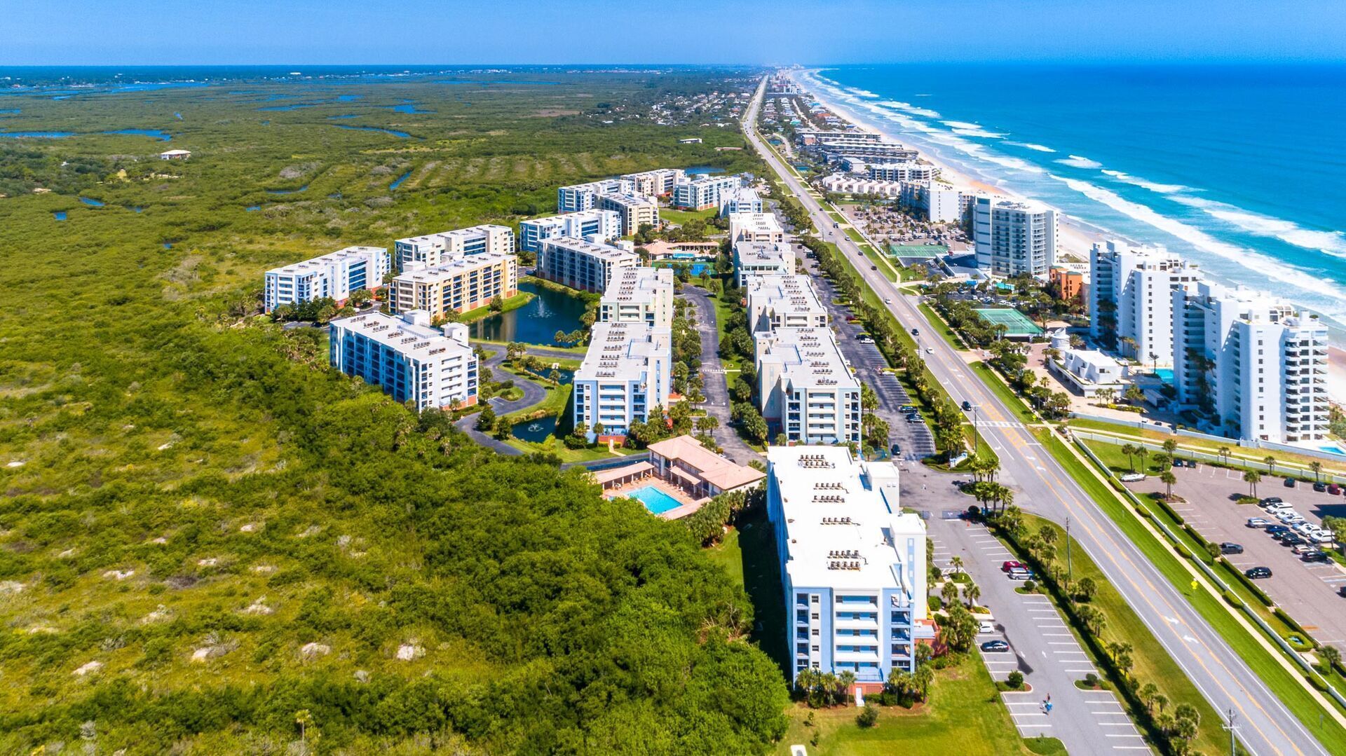 Een kustgebied met woonhuizen, moderne appartementencomplexen, een weg en een strand.