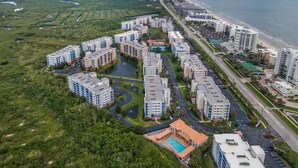 An aerial view of a coastal residential area with multiple high-rise buildings, a beach, and a marina.