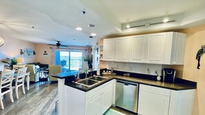 A compact kitchen with white cabinets, a dishwasher, and a dining area with a table and chairs.