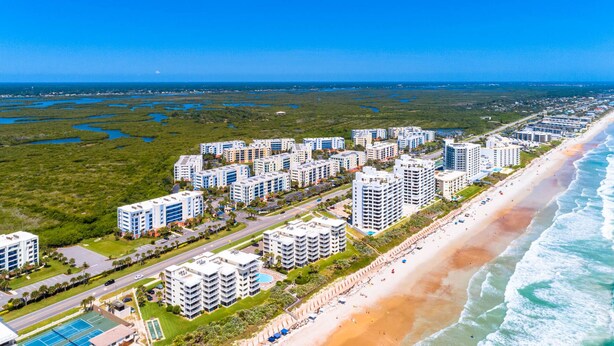 A coastal residential area with high-rise buildings, a beach, and a clear view of the ocean.