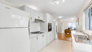 A modern kitchen with white cabinetry, a built-in oven, and a large window providing a view of the outdoors.