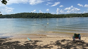 Une plage d’où l’on a une vue dégagée sur le lac, une chaise et un petit bateau.