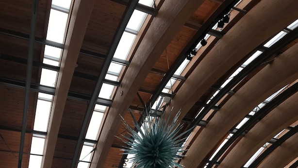 Un intérieur moderne avec un plafond haut, de grandes fenêtres et une structure décorative centrale.