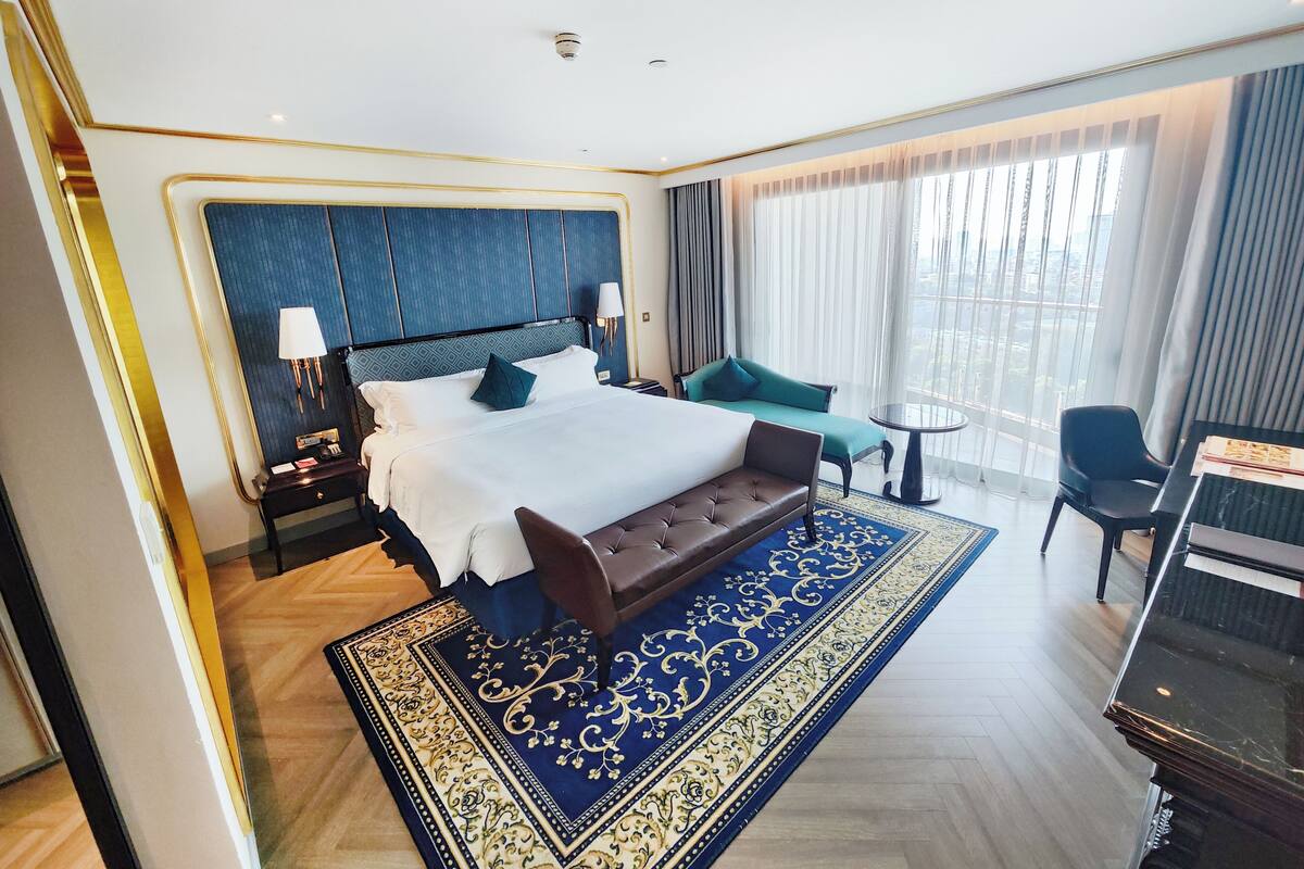 A hotel room with a large bed, a sofa, a small table, and a piano.