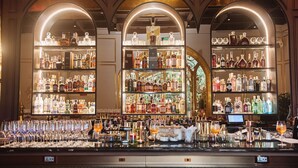 Un bar con varias estanterías llenas de botellas de licor, vasos y una caja registradora.