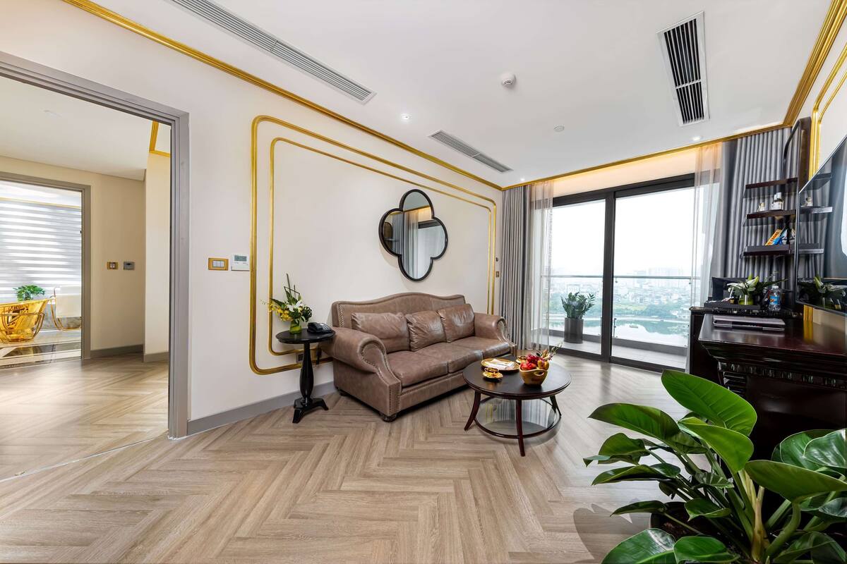 A modern living room with a sofa, a coffee table, and a large window offering a city view.
