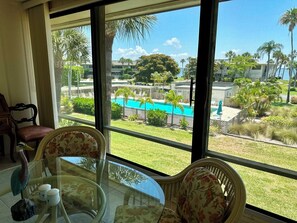 A room with a large window overlooking a pool and a well-maintained garden. - West Bay Point Moorings 155 - Condo 2 Bedroom/ 2 Bath , maximum occupancy of 4 people. (Holmes Beach)