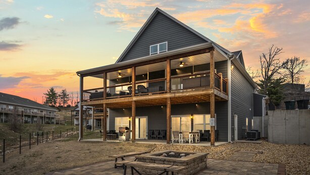 A two-story house with a covered porch, a fire pit, and a patio area. - 10BR Branson Lodge • Sleeps 32 • New Hot Tub • Near Hwy 76 (Branson)