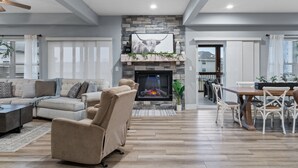 A spacious living room with a fireplace, a dining area, and a view of the outside. - 10BR Branson Lodge • Sleeps 32 • New Hot Tub • Near Hwy 76 (Branson)