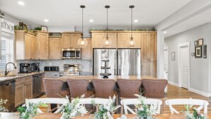 A modern kitchen with wooden cabinets, stainless steel appliances, and a central island with seating. - 10BR Branson Lodge • Sleeps 32 • New Hot Tub • Near Hwy 76 (Branson)