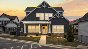 A two-story house with a front porch, stone foundation, and a garage. - 10BR Branson Lodge • Sleeps 32 • New Hot Tub • Near Hwy 76 (Branson)
