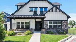 A two-story house with a gabled roof, a front porch, and a stone accent wall. - Breathtaking Home! *In Town*Fire-Pits* Indoor Pool*Yard Games*Golf View* (Branson)