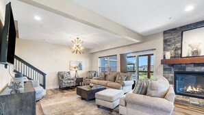 A spacious living room with a fireplace, a large window, and a staircase. - Breathtaking Home! *In Town*Fire-Pits* Indoor Pool*Yard Games*Golf View* (Branson)
